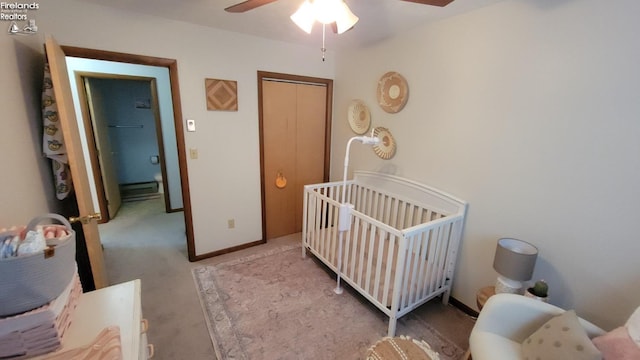 bedroom featuring baseboards, a ceiling fan, carpet floors, a nursery area, and a closet