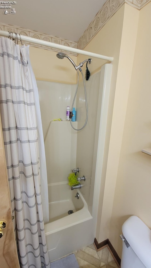 bathroom featuring baseboards, toilet, and shower / bath combo with shower curtain