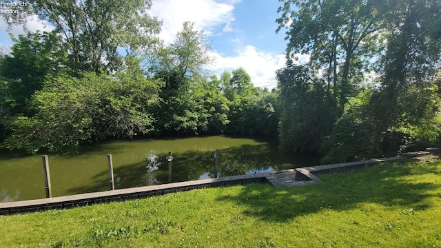 view of dock with a yard and a water view