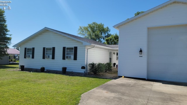 view of home's exterior with a garage, a lawn, driveway, and an outdoor structure