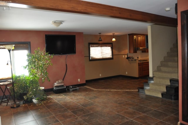 unfurnished living room with stairway, beam ceiling, and baseboards