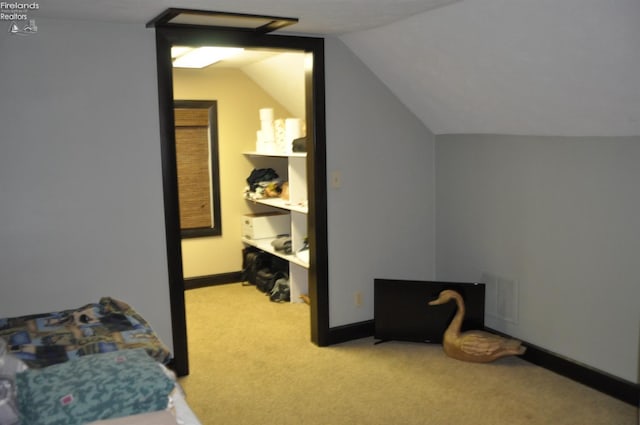 carpeted bedroom featuring lofted ceiling, visible vents, and baseboards