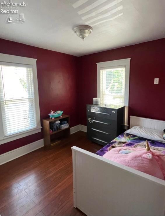 bedroom with multiple windows, baseboards, and dark wood finished floors