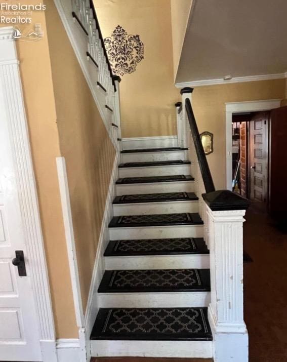 stairway with crown molding and baseboards