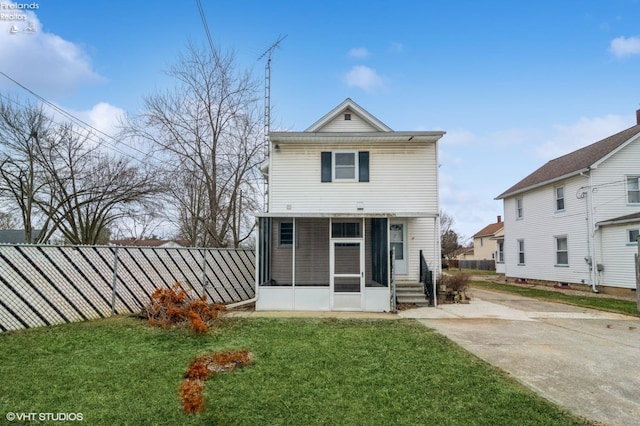 rear view of property with a sunroom, a yard, and fence