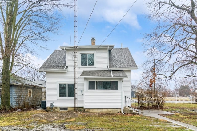 rear view of house featuring roof with shingles, a chimney, and fence