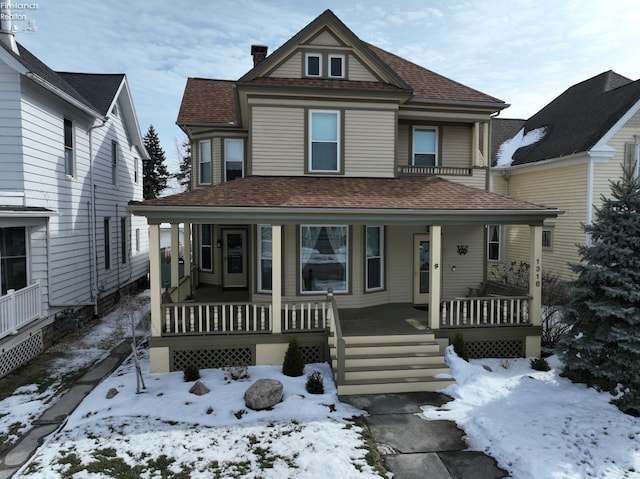 victorian house featuring covered porch and roof with shingles