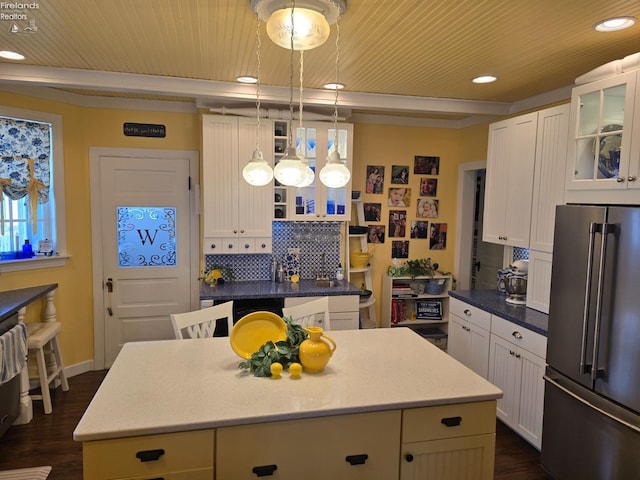 kitchen featuring high end refrigerator, wooden ceiling, a center island, white cabinetry, and backsplash