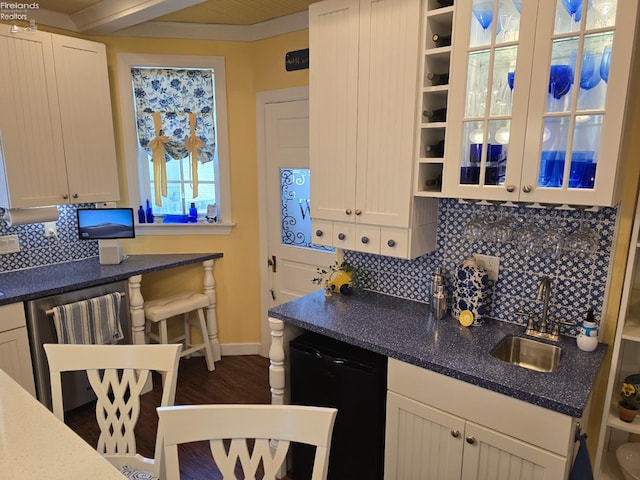 kitchen featuring decorative backsplash, white cabinets, dishwasher, and a sink