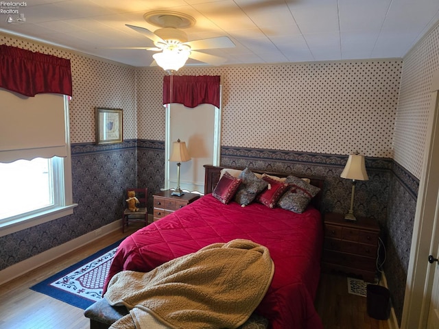 bedroom featuring wallpapered walls, baseboards, a ceiling fan, and wood finished floors