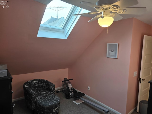 exercise room featuring lofted ceiling with skylight, carpet, ceiling fan, and baseboards