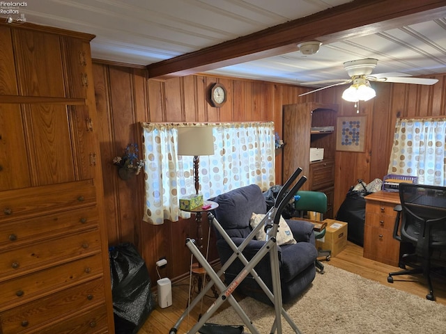 office space featuring light wood finished floors, wood walls, beam ceiling, and a ceiling fan