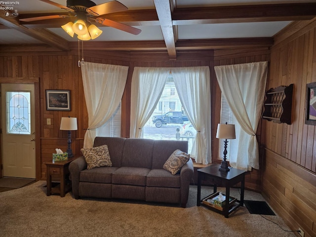 carpeted living area with a ceiling fan, coffered ceiling, beam ceiling, and wooden walls