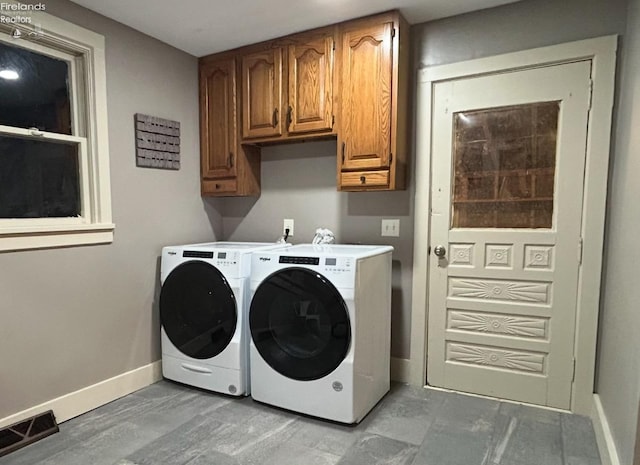 clothes washing area with washing machine and dryer, cabinet space, visible vents, and baseboards