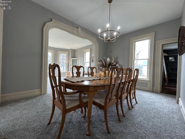 dining space with arched walkways, carpet flooring, and plenty of natural light