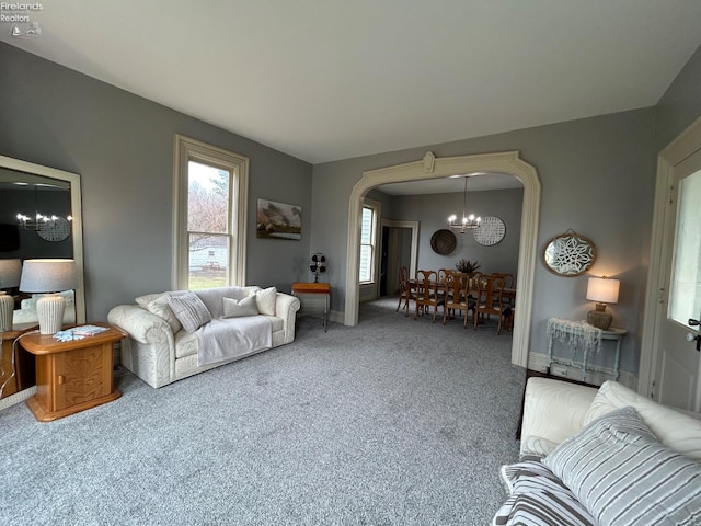 living area with carpet floors, baseboards, arched walkways, and a notable chandelier