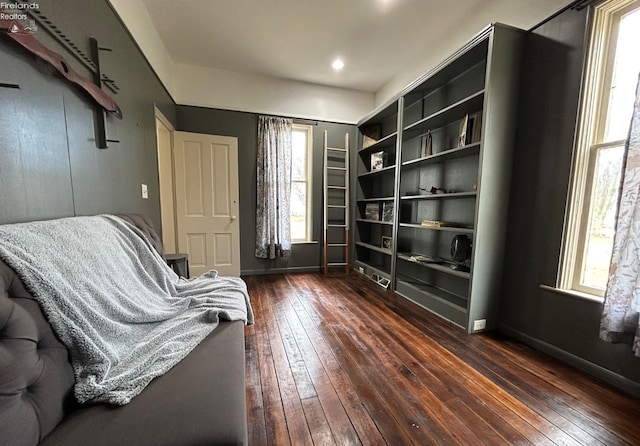 sitting room featuring built in shelves, dark wood finished floors, and baseboards