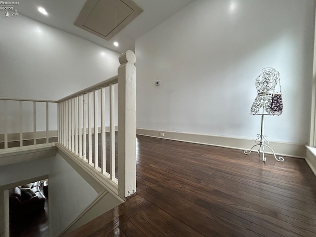 hall with wood-type flooring, attic access, and baseboards