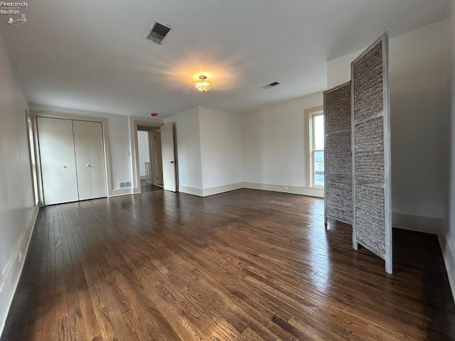 unfurnished living room featuring dark wood-style floors and visible vents