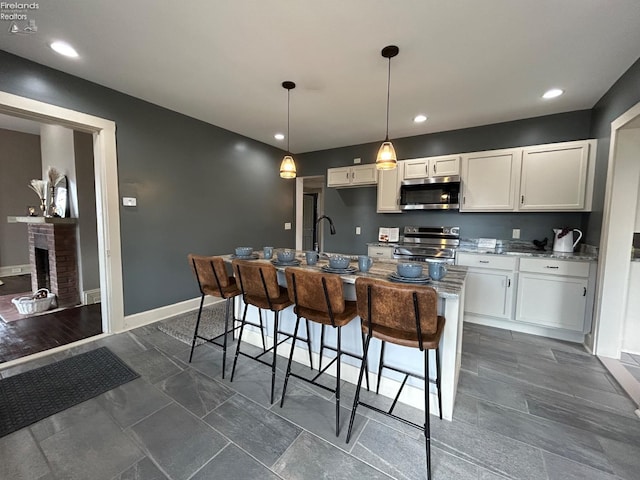 kitchen with stainless steel appliances, a fireplace, baseboards, white cabinets, and light stone countertops