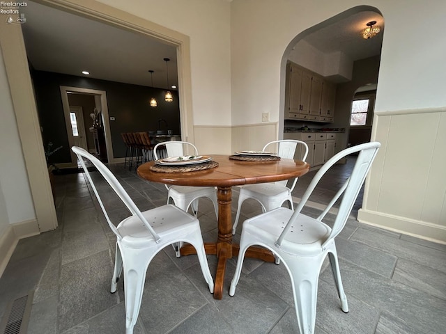 dining space with arched walkways, wainscoting, visible vents, and baseboards