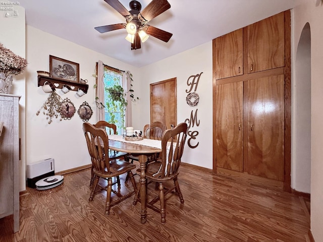 dining room featuring arched walkways, ceiling fan, baseboards, and wood finished floors