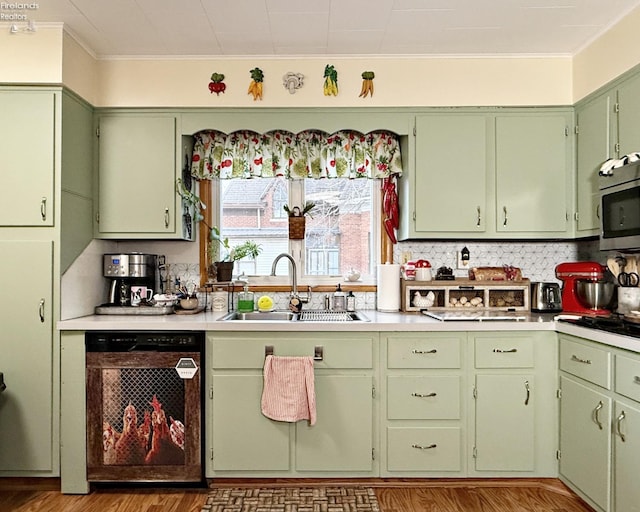 kitchen with a sink, green cabinets, light countertops, dishwasher, and stainless steel microwave