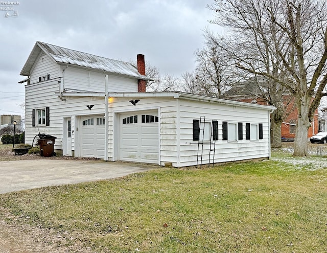 exterior space featuring metal roof, driveway, a yard, and a chimney