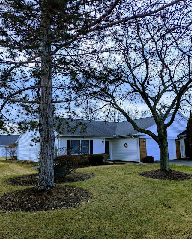 view of front facade with a garage, brick siding, driveway, and a front yard