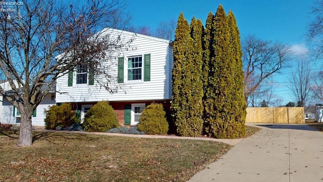 split level home featuring fence and a front yard