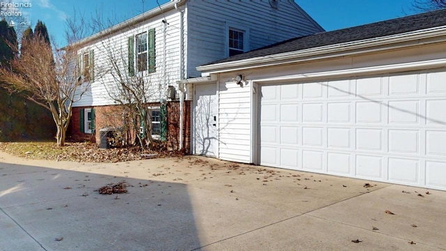 view of property exterior featuring concrete driveway, brick siding, and an attached garage