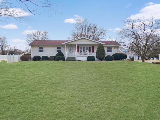 view of front of property with covered porch, fence, and a front lawn