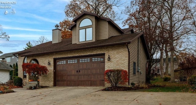 view of front of property with driveway, brick siding, a chimney, and an attached garage