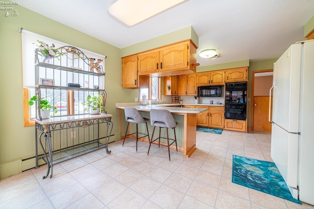 kitchen featuring a baseboard radiator, a breakfast bar, a peninsula, light countertops, and black appliances