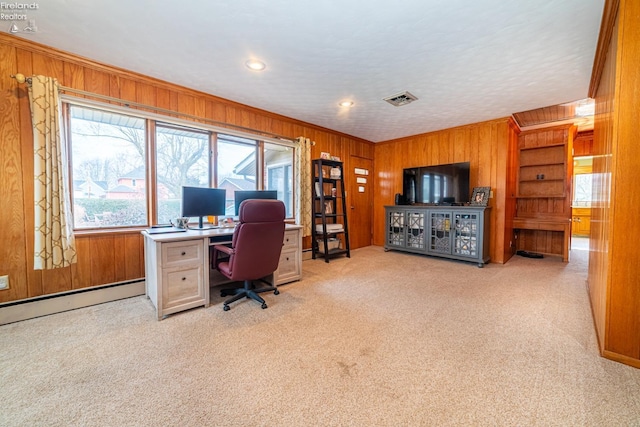 carpeted home office featuring wood walls, a baseboard radiator, visible vents, and ornamental molding