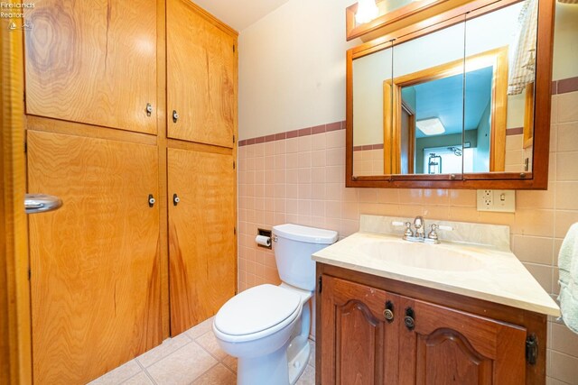 bathroom featuring toilet, tile walls, and vanity