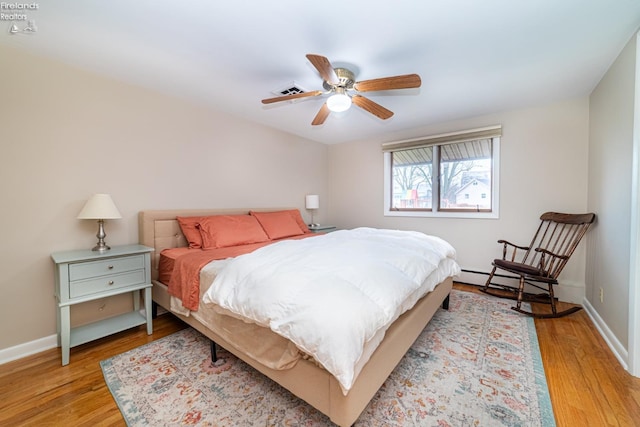 bedroom with ceiling fan, light wood finished floors, baseboard heating, and baseboards