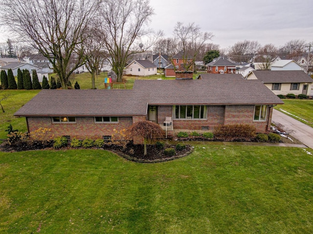 view of front of home featuring a front lawn, a residential view, brick siding, and a shingled roof