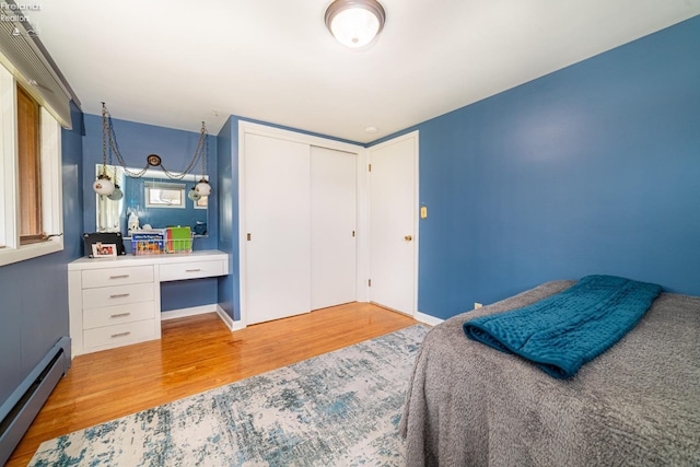 bedroom featuring a baseboard radiator, a closet, and wood finished floors