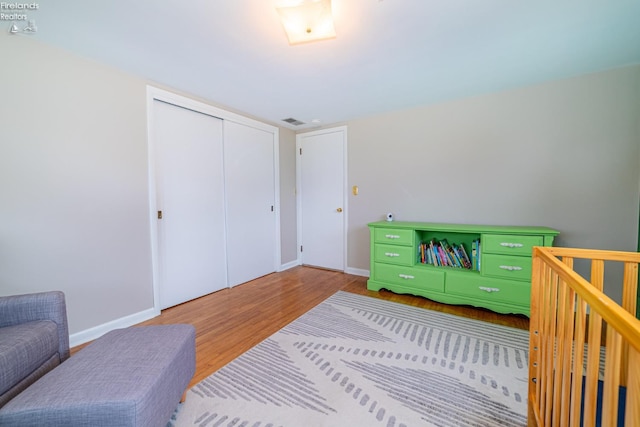 bedroom featuring a closet, wood finished floors, visible vents, and baseboards