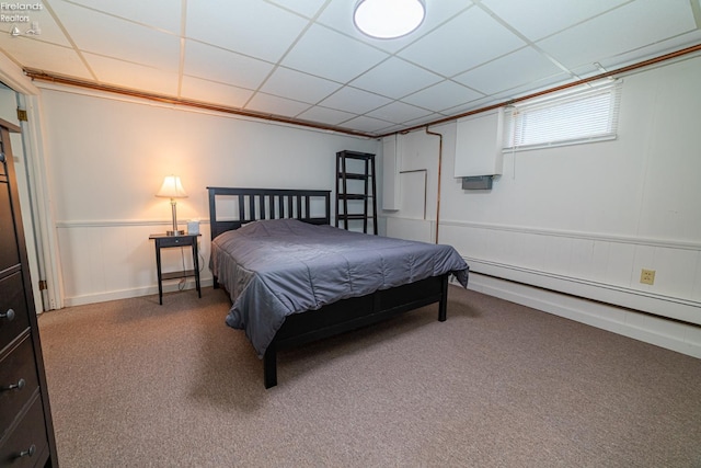 bedroom with wainscoting, a drop ceiling, and a baseboard radiator