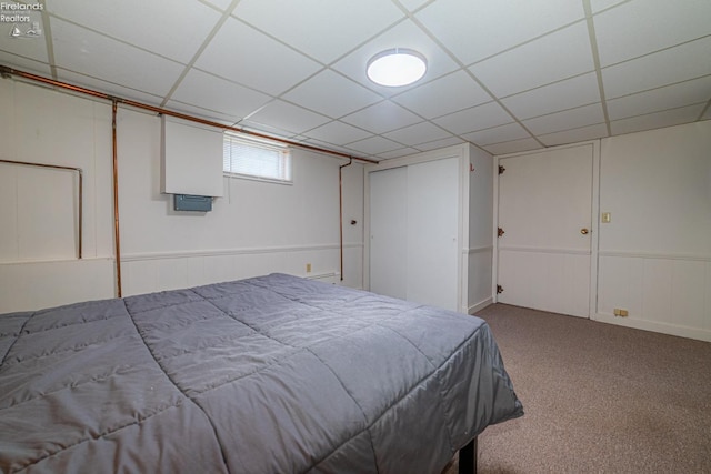 carpeted bedroom featuring a closet and a drop ceiling