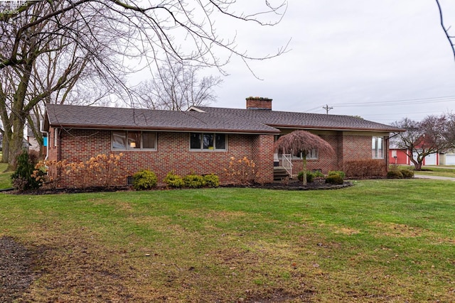 ranch-style house with a chimney, a front lawn, and brick siding