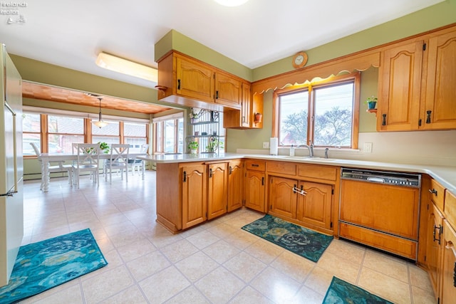 kitchen with a wealth of natural light, light countertops, paneled dishwasher, a sink, and a peninsula