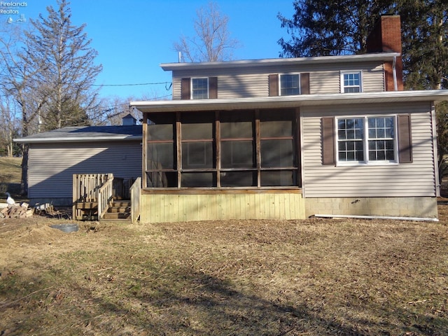 back of property with a chimney and a sunroom