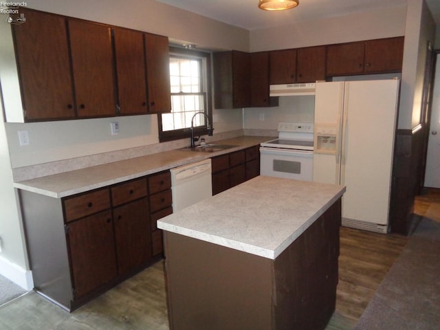 kitchen with white appliances, dark wood-style floors, light countertops, under cabinet range hood, and a sink