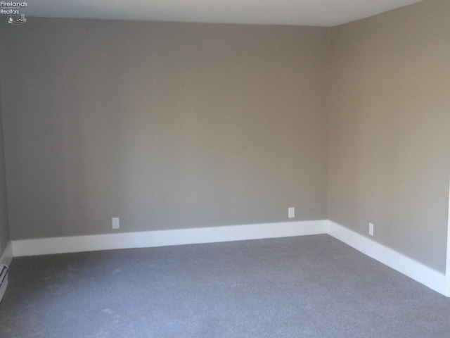 empty room with a baseboard radiator, baseboards, and dark carpet