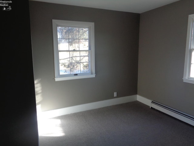 unfurnished room featuring baseboards, dark carpet, a baseboard radiator, and a healthy amount of sunlight