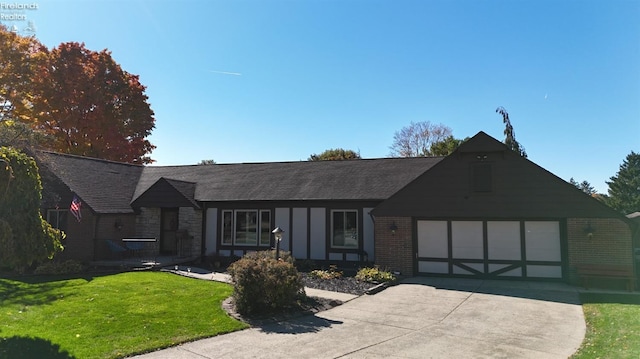 view of front of home featuring brick siding, a garage, stone siding, driveway, and a front lawn