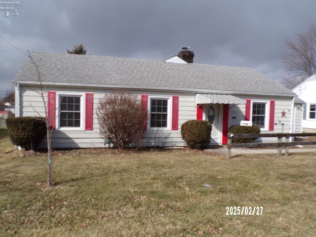 ranch-style home with roof with shingles, a chimney, and a front yard